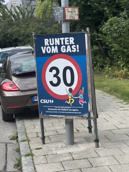 A street sign shows a speed limit of 30 km/h with the text "RUNTER VOM GAS!" (Reduce the gas!). It features illustrations of two children playing. The sign is sponsored by CSU, with details for a community meeting listed below