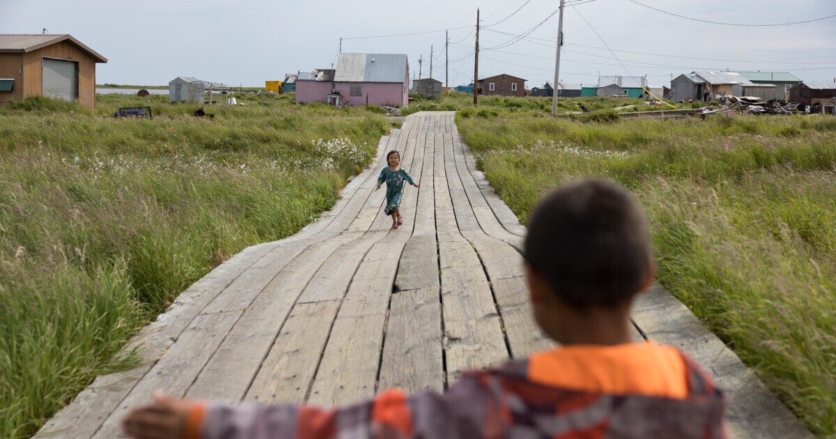 Mavis Alexie-Felix and Stephan Dock play on the boardwalks that run through the village. Permafrost heaves cause the boardwalk to become uneven and difficult to maintain. July 24, 2024 in Nunapitchuk, Alaska.