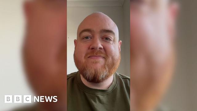 Artificial intelligence education expert Dan Fitzpatrick wearing a green top on a plain background. He has a beard and has his mouth closed