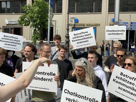 Demoteilnehmer.innen mit Protestschildern. Im Hintergrund ist die Europäische Vertretung zu erkennen. 