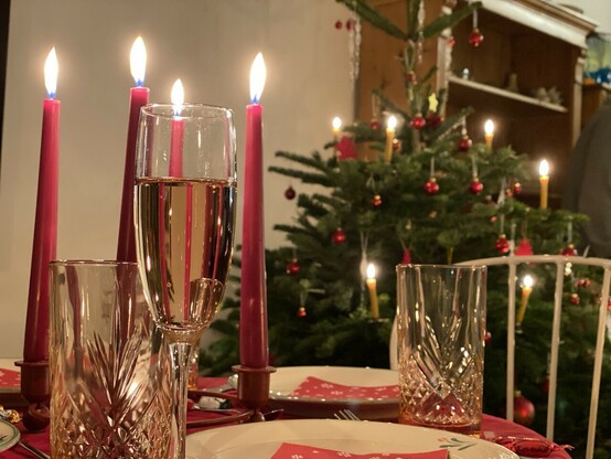 Weihnachtsbaum, davor ein kleiner gedeckter Tisch mit Kerzen. 