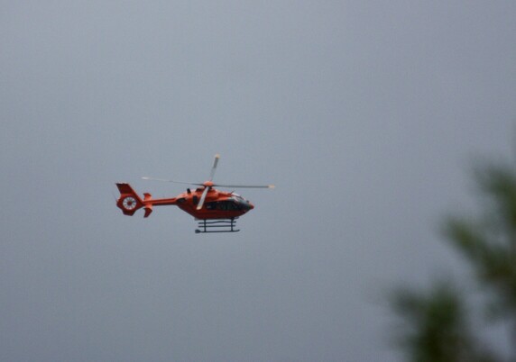 Orangefarbener Rettungshubschrauber im Landeanflug von rechter Seite/Oberseite.