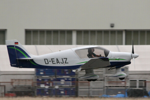 A Robin DR401 single-engine low-wing light aircraft just before touchdown
