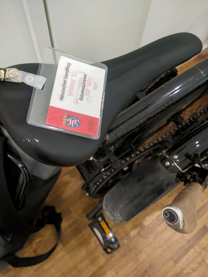 Ein gefaltetes Brompton-Faltrad, darauf liege ein Gästeausweis des hessischen Landtags