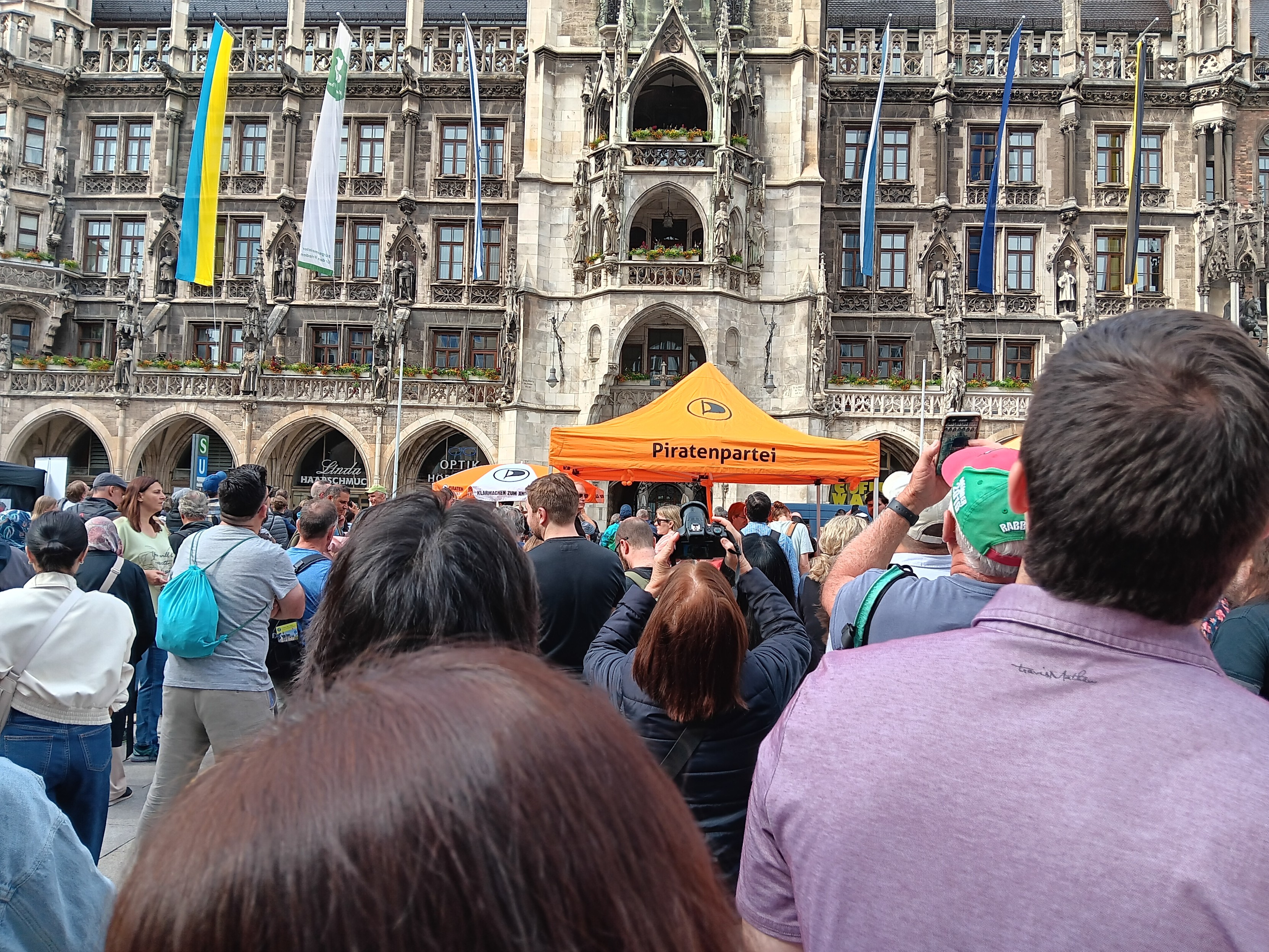Eine große Menschenmenge drängt sich vor dem Piratenpavillion. Dahinter das Münchner Rathaus.