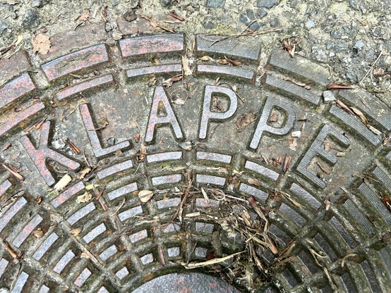 A metal manhole cover inscribed with the word 