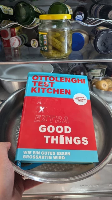 Yotam Otzolenghi - Otzolenghi Test Kitchen - Extra Good Things
Das Buch liegt in einer Bratpfanne, die von einer Hand vor einem offenen und nur spärlich mit Nahrung bestückten Kühlschrank gehalten wird.