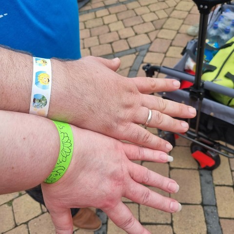 Zwei arme mit den Armbändern für Behinderte (Biene Maja) und ihre Begleitperson (grün).