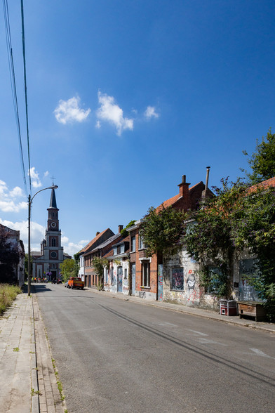 Straße mit Hausreihe. Die Häuser sind verlassen und voller Graffiti. Am Ende eine Kirche