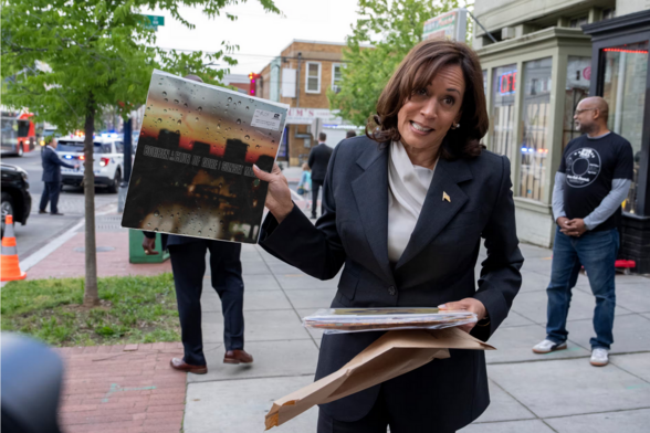 Kamala Harris steht auf der Straße und hält einen Stapel Schallplatten in der Hand. Eine Platte hält sie hoch, es ist Sunset Mission von Bohren & Der Club Of Gore. (Es ist ein generiertes Bild, in dem das Plattencover eingefügt wurde.)