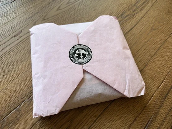 ein hübsch in rosa Papier eingeschlagenes T-Schirt (nicht sichtbar) mit einem runden Sticker zugeklebt, der Björn Höcke mit Hitlergruß zeigt in schwarz-weiß von Zentrum für Politische Schönheit