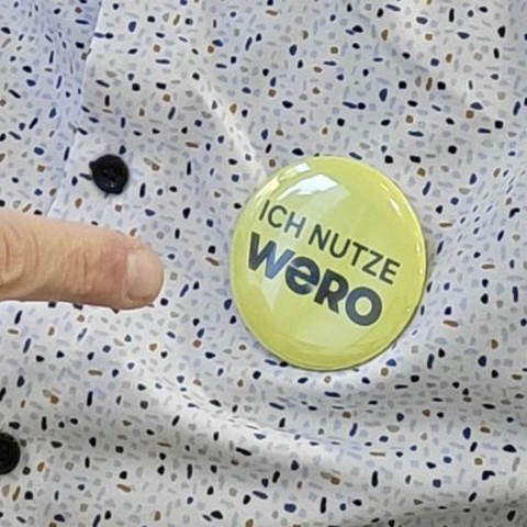Anstecker mit gelbem Hintergrund auf einem Hemd mit dem Text „Ich nutze WERO“.