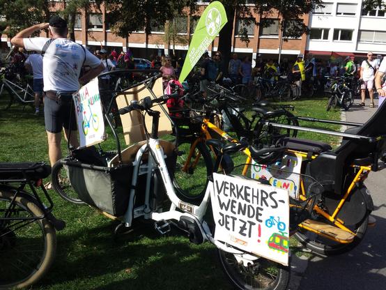 Viele Fahrräder vor der Stadtbücherei, unter anderem ein Lastenrad mit einem Schild "Verkehrswende jetzt!" 