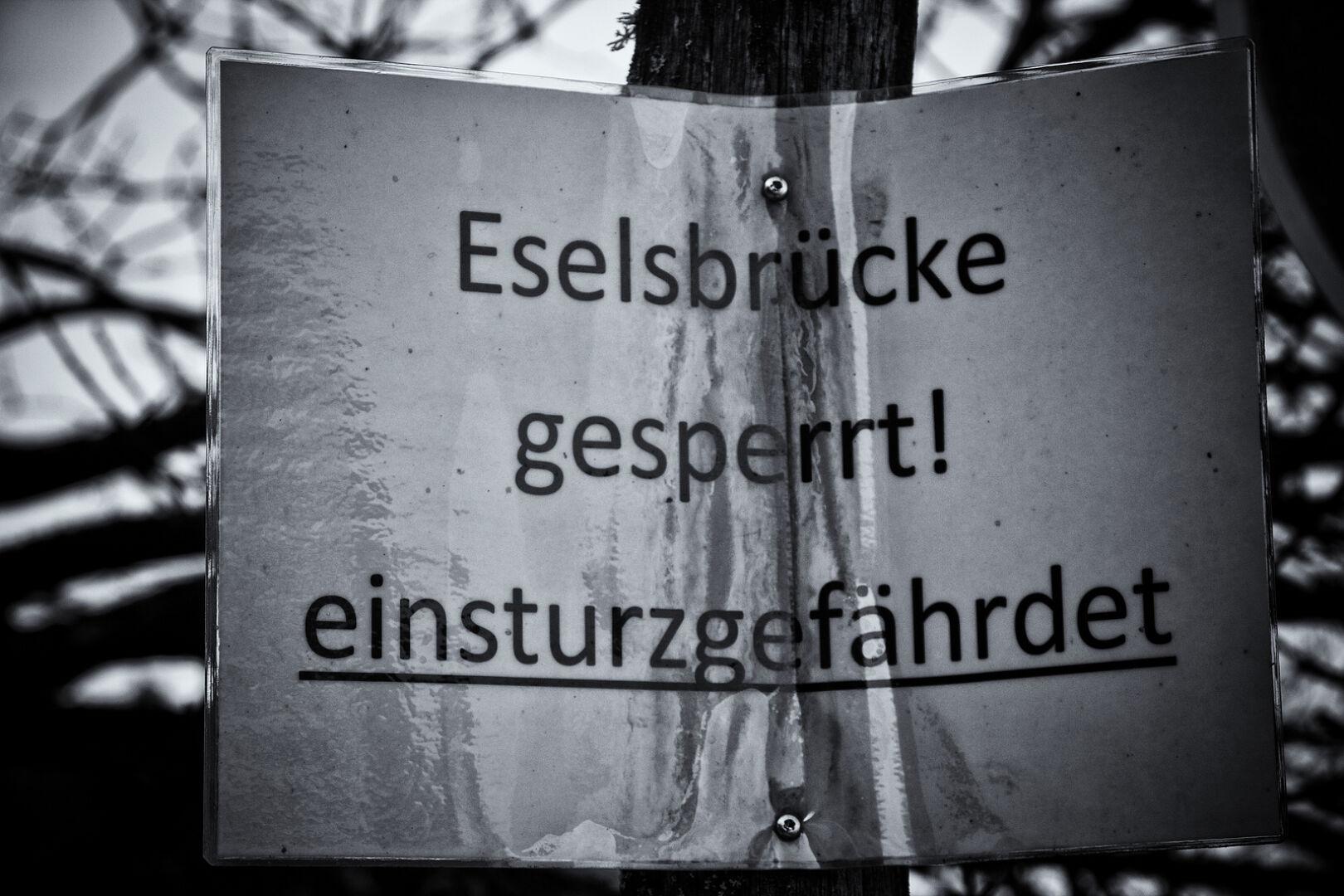 Laminiertes DinA4 Blatt an einem Baum. Aufschrift: Eselsbrücke gesperrt! Einsturzgefährdet.