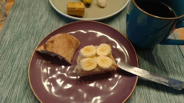 Frühstücksteller mit Banaenscheiben auf einem Stück Brot.
