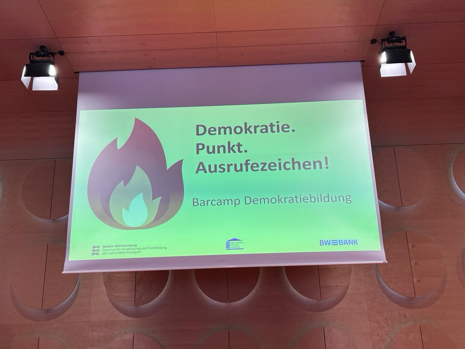 Veranstaltundvildschirm zum Barcamp Demokratiebildung im Hospitalhof Stuttgart mit der Aufschrift: Demokratie. Punkt. Ausrufezeichen!